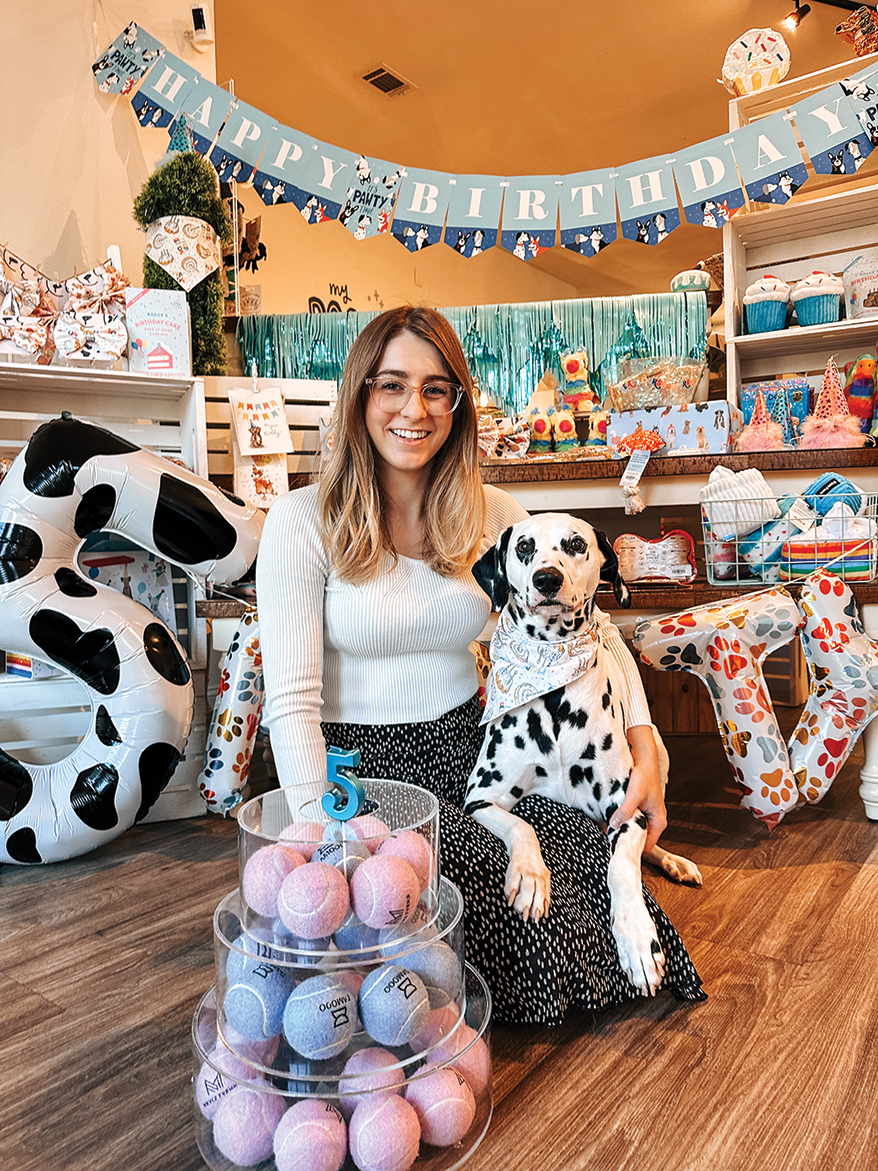 Maddie Shutts and Blaze pose in front of the store’s “5th Birthday” display, filled with celebration products.